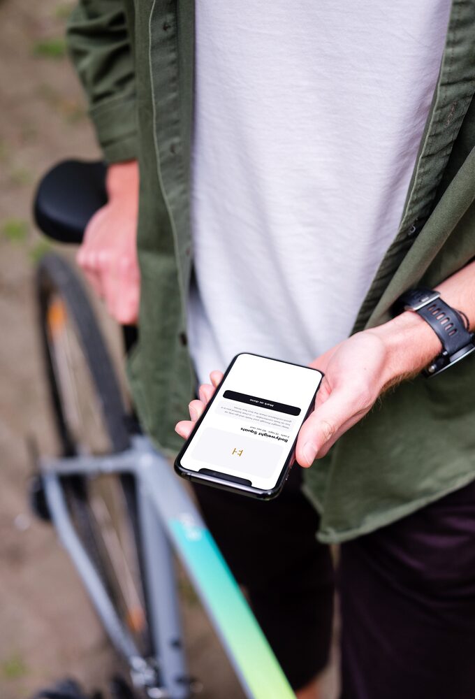 A man standing beside a bike, the app’s strength session open on the phone in his hand
