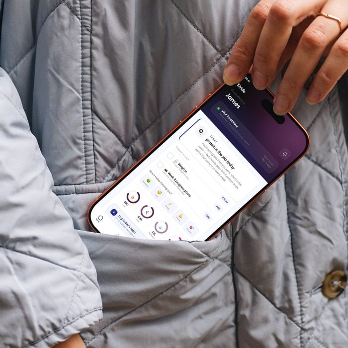 A phone being slipped into a coat pocket, the app’s home screen still lit