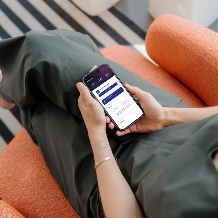 Someone sitting back on a sofa reading the app on their phone